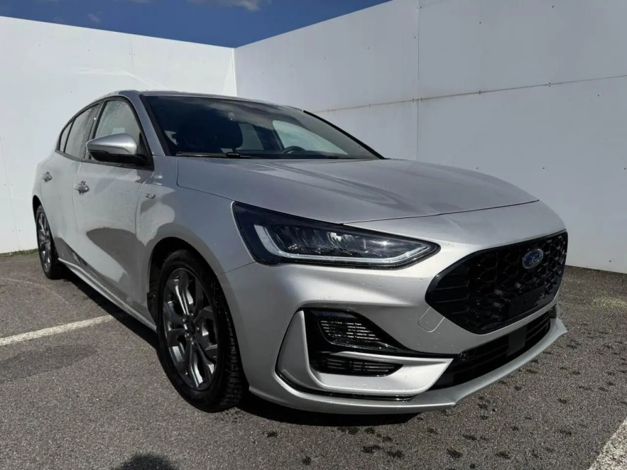 Ford Focus IV ST-Line X gris Moondust métal vue 3/4 avant avec calandre noire et jantes alliage 17 pouces.