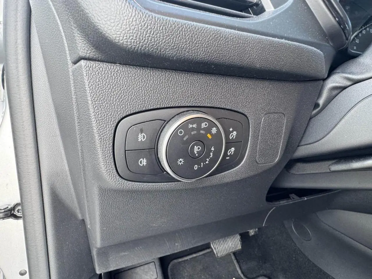 Gros plan sur le panneau de commande des phares côté gauche intérieur d'une Ford Focus IV gris Moondust Metal.