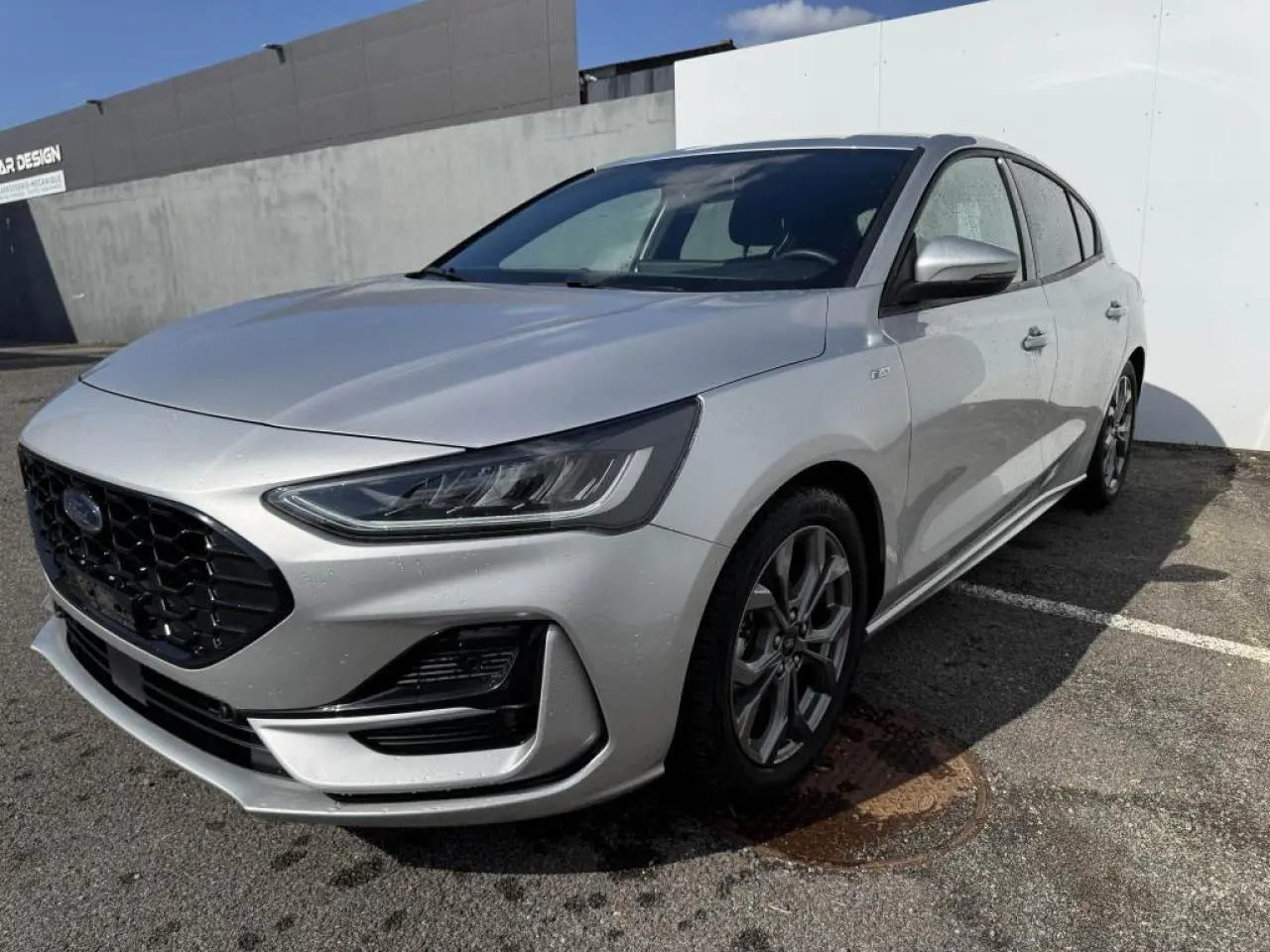 Ford Focus IV ST-Line X gris Moondust métal vue 3/4 avant avec calandre noire et jantes alliage 17 pouces.