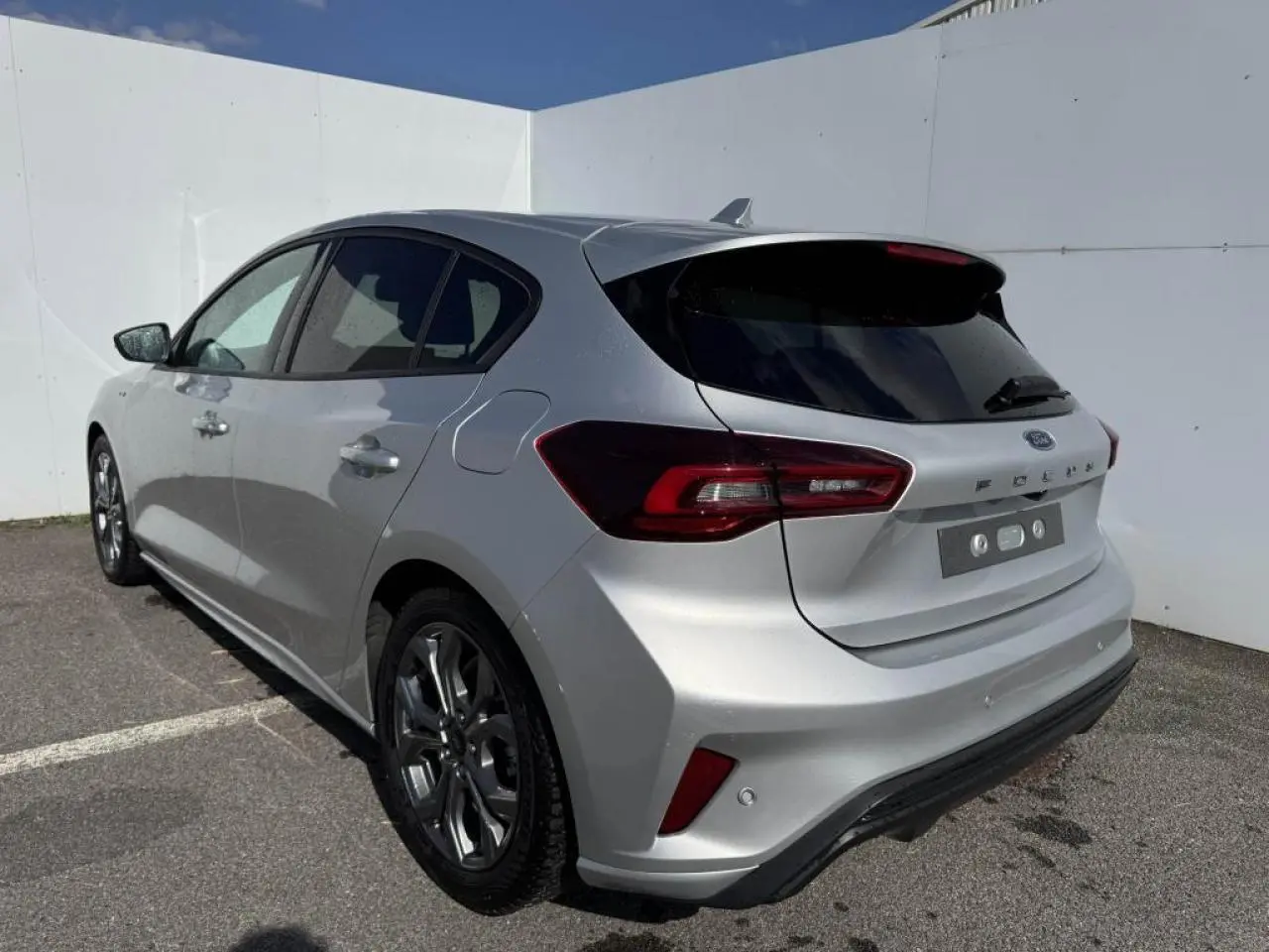 Ford Focus IV ST-Line X gris Moondust métal vue 3/4 arrière droit avec jantes alliage 17'' et becquet carrosserie