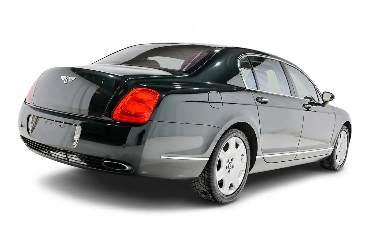 Vue 3/4 arrière droite d'une Bentley Continental Flying Spur vert foncé avec feux arrière rouges et jantes argentées.