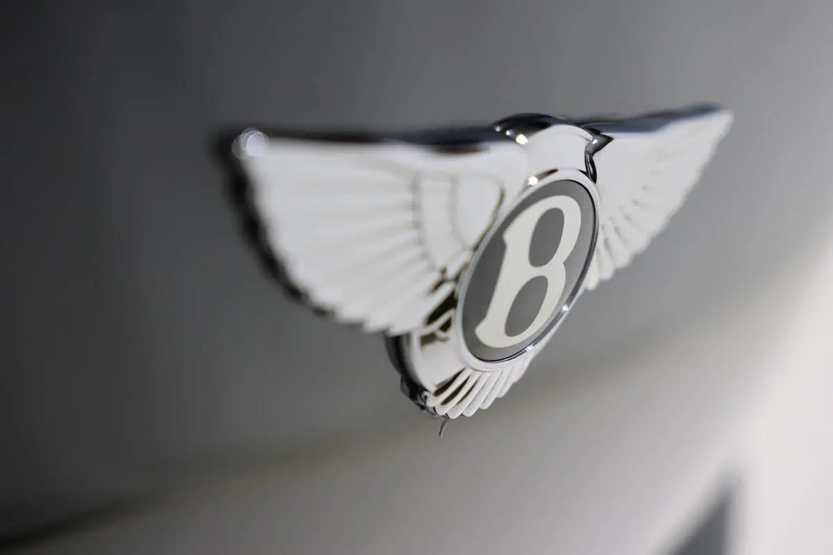 Gros plan sur l'emblème ailé Bentley chromé sur fond vert foncé du capot d'une Continental Flying Spur 2006.