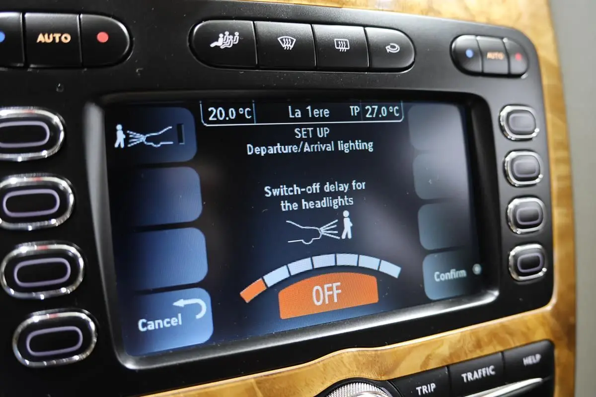 Écran central de la Bentley Continental Flying Spur 2006 montrant le réglage d’éclairage, entouré de bois clair et boutons noirs.