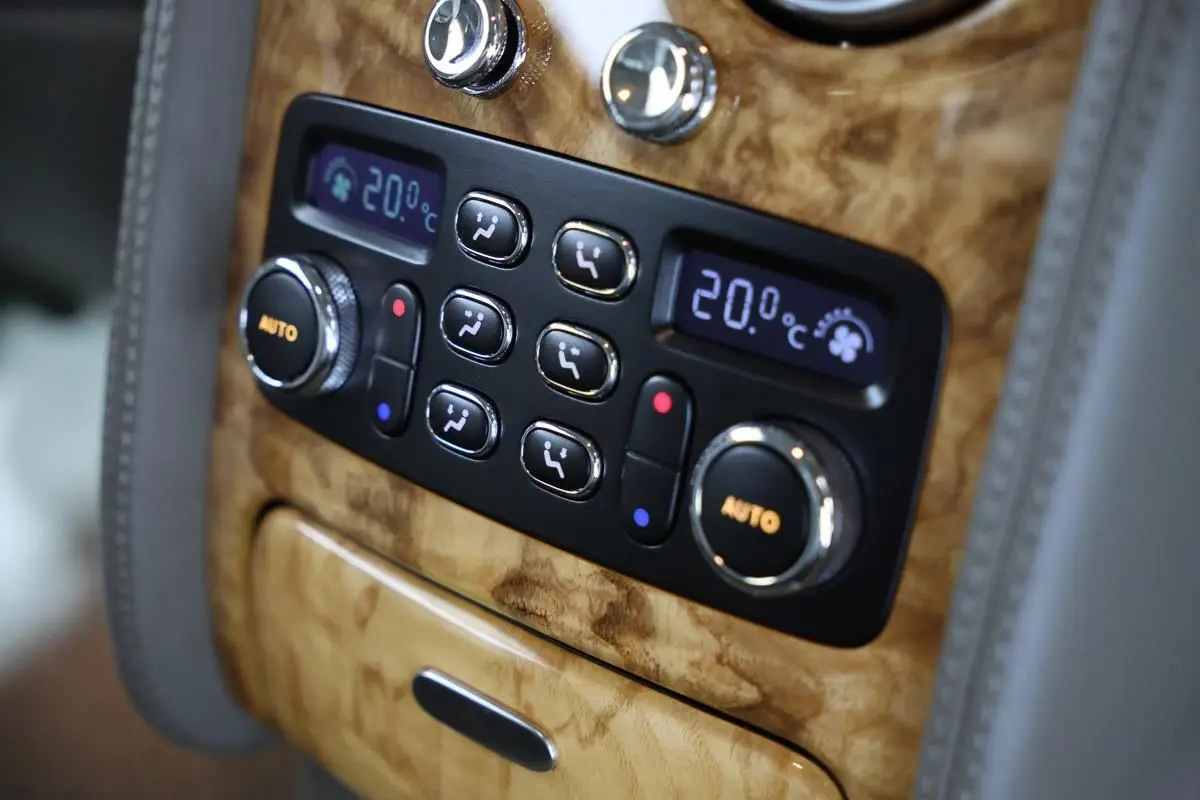 Détail de la console centrale en bois clair avec commandes de climatisation digitale de la Bentley Continental Flying Spur.
