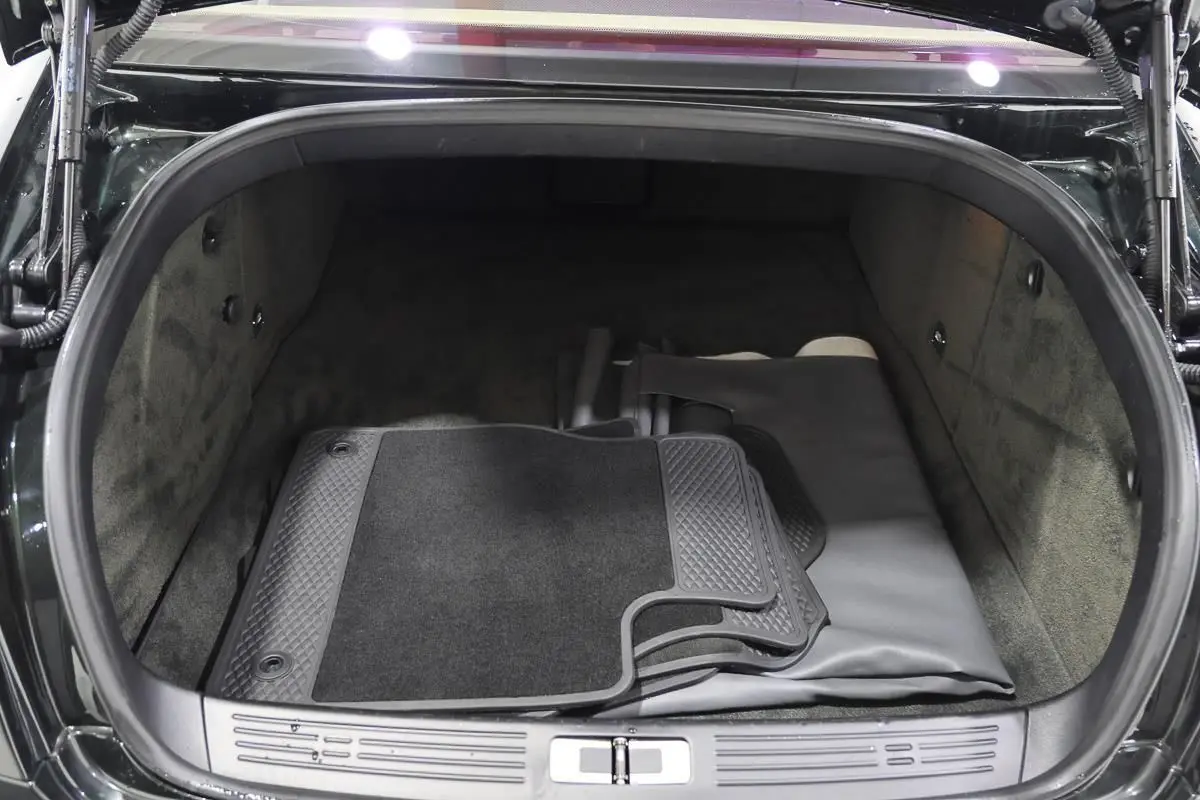 Vue du coffre ouvert d'une Bentley Continental Flying Spur 2006 vert foncé, montrant tapis et revêtement intérieur gris.