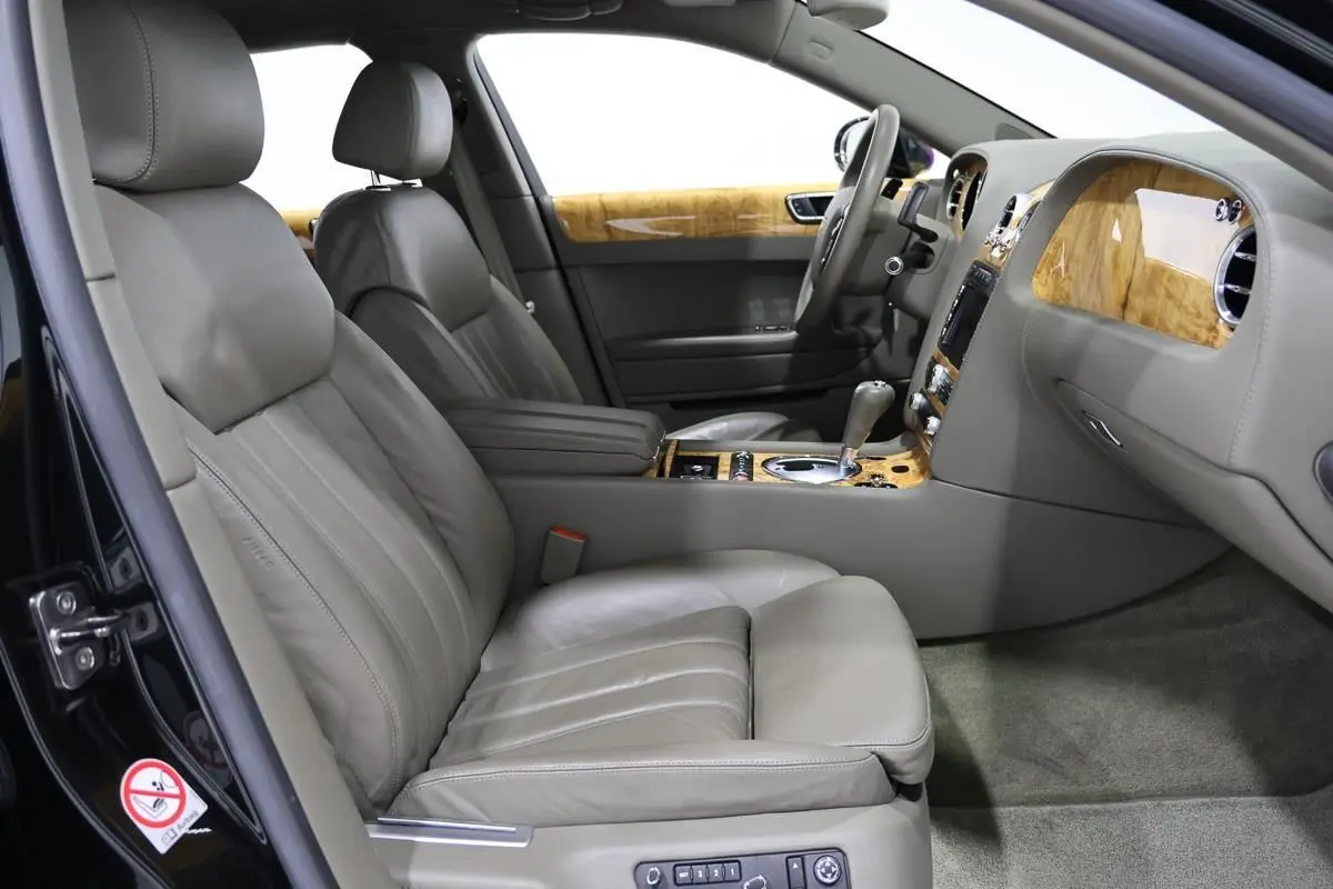 Vue intérieure côté conducteur de la Bentley Continental Flying Spur 2006, sièges cuir gris et boiseries claires élégantes.
