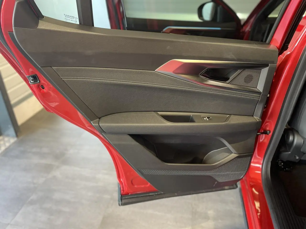 Vue intérieure côté gauche de la porte arrière rouge du Renault Rafale 2025 avec inserts textiles et surpiqûres argent.