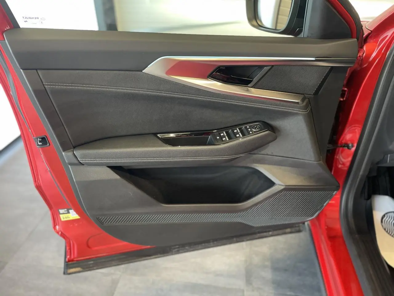 Vue intérieure de la porte avant gauche rouge de la Renault Rafale 2025 avec garniture textile refined et commandes électriques.
