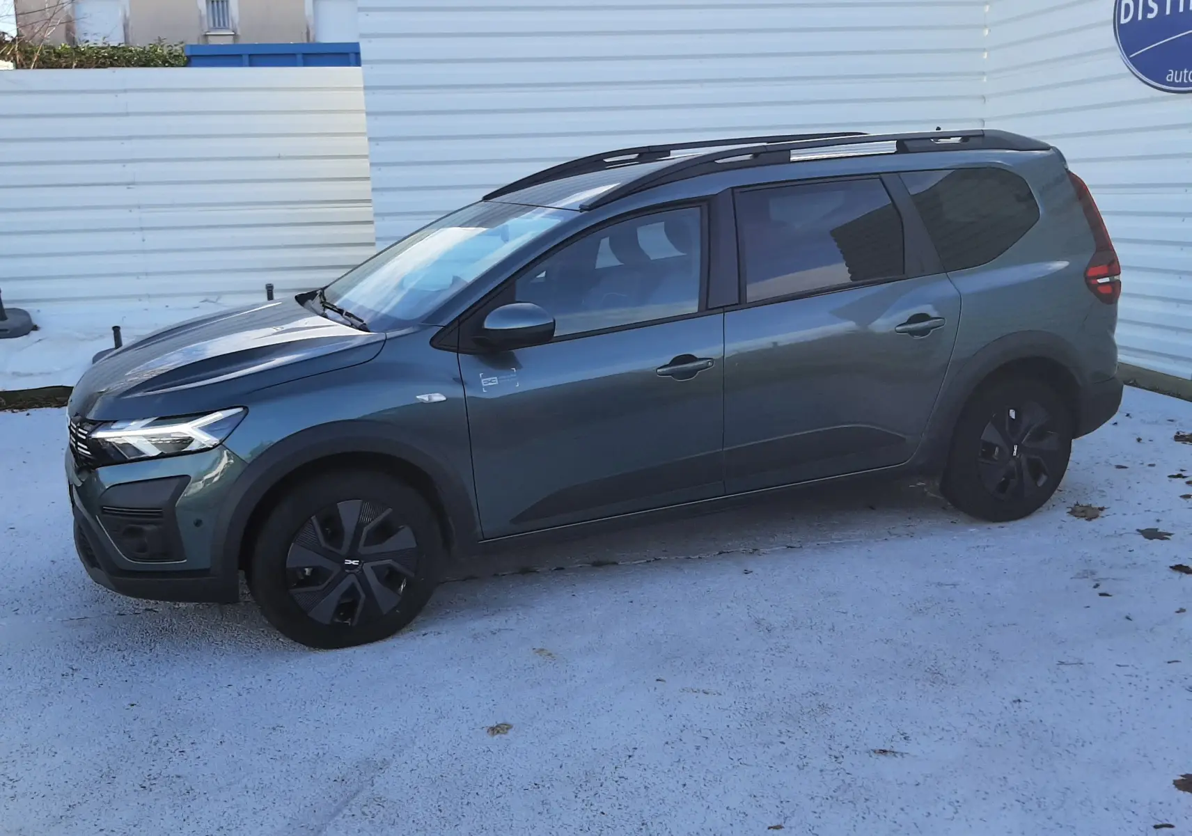 Gros plan sur l’avant gauche du Dacia Jogger vert cèdre métal, mettant en valeur le phare LED et la calandre noire.