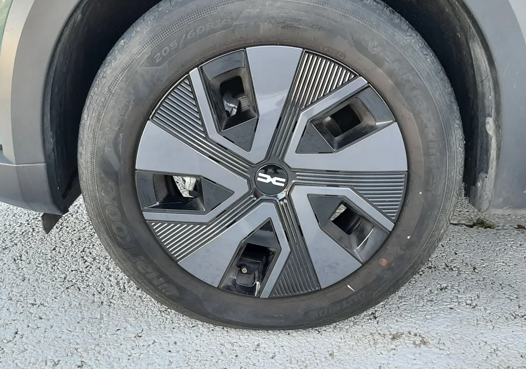 Gros plan sur la roue avant droite du Dacia Jogger vert cèdre métal, avec jante au design moderne noir et gris.