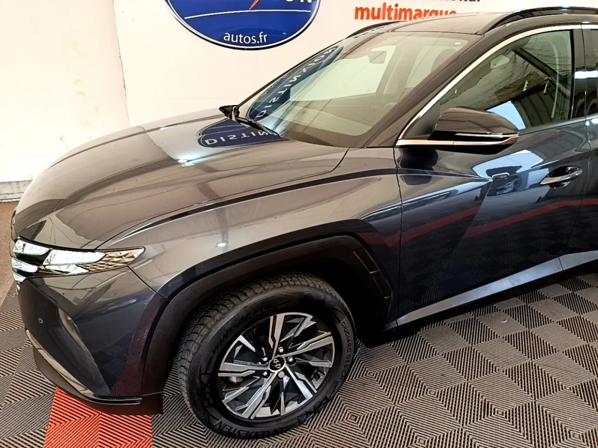 Vue 3/4 avant droit du Hyundai Tucson gris foncé 2022 avec jantes alliage et phares LED fins.