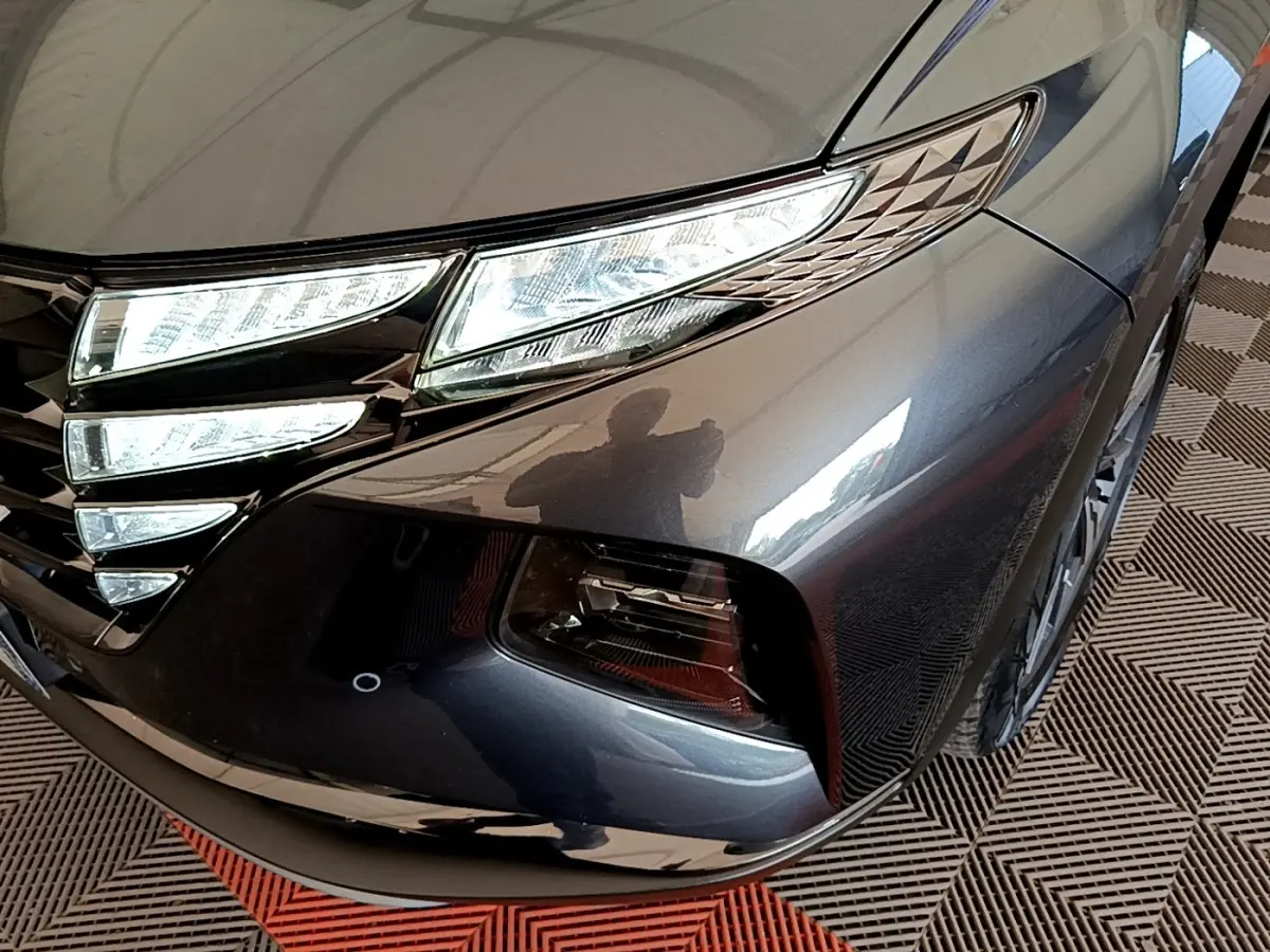 Gros plan sur l'avant droit gris foncé du Hyundai Tucson 1.6 Hybrid 230 avec phares LED et calandre distinctive.