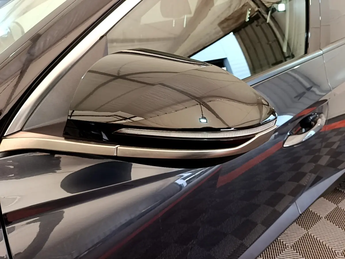 Gros plan sur le rétroviseur côté gauche gris foncé du Hyundai Tucson 1.6 Hybrid 230 Creative avec clignotant intégré.