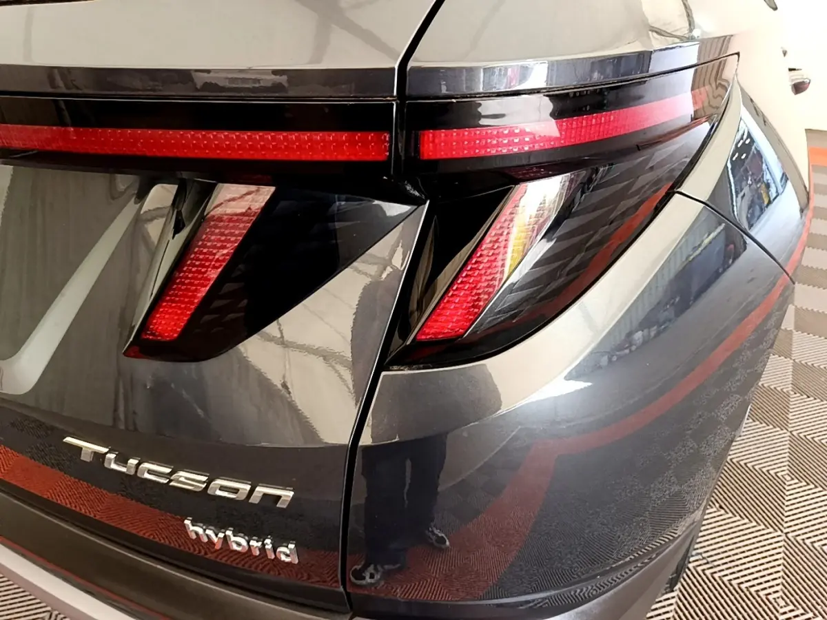 Vue rapprochée arrière droite du Hyundai Tucson gris foncé avec feux LED et logo hybride visible.