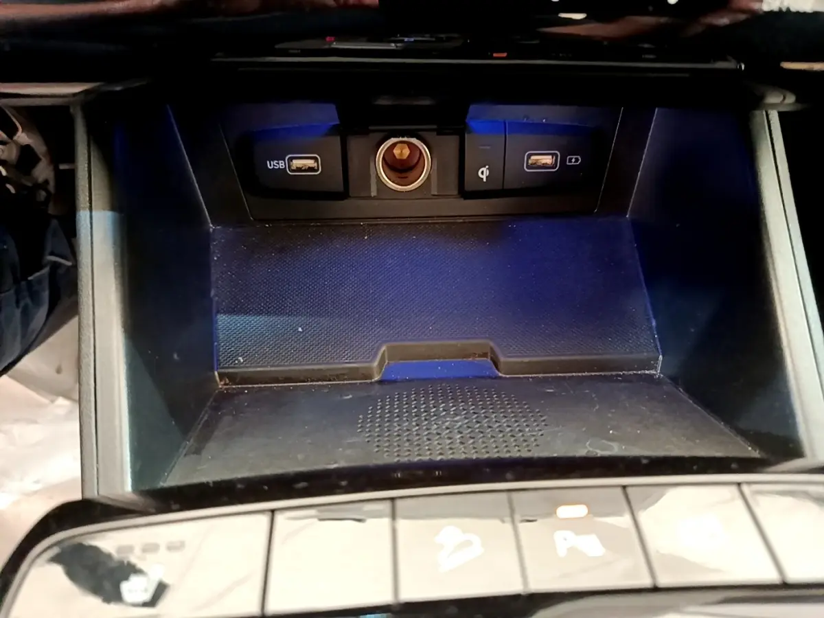 Gros plan sur la console centrale du Hyundai Tucson gris foncé, montrant ports USB et prise 12V avec éclairage bleu.