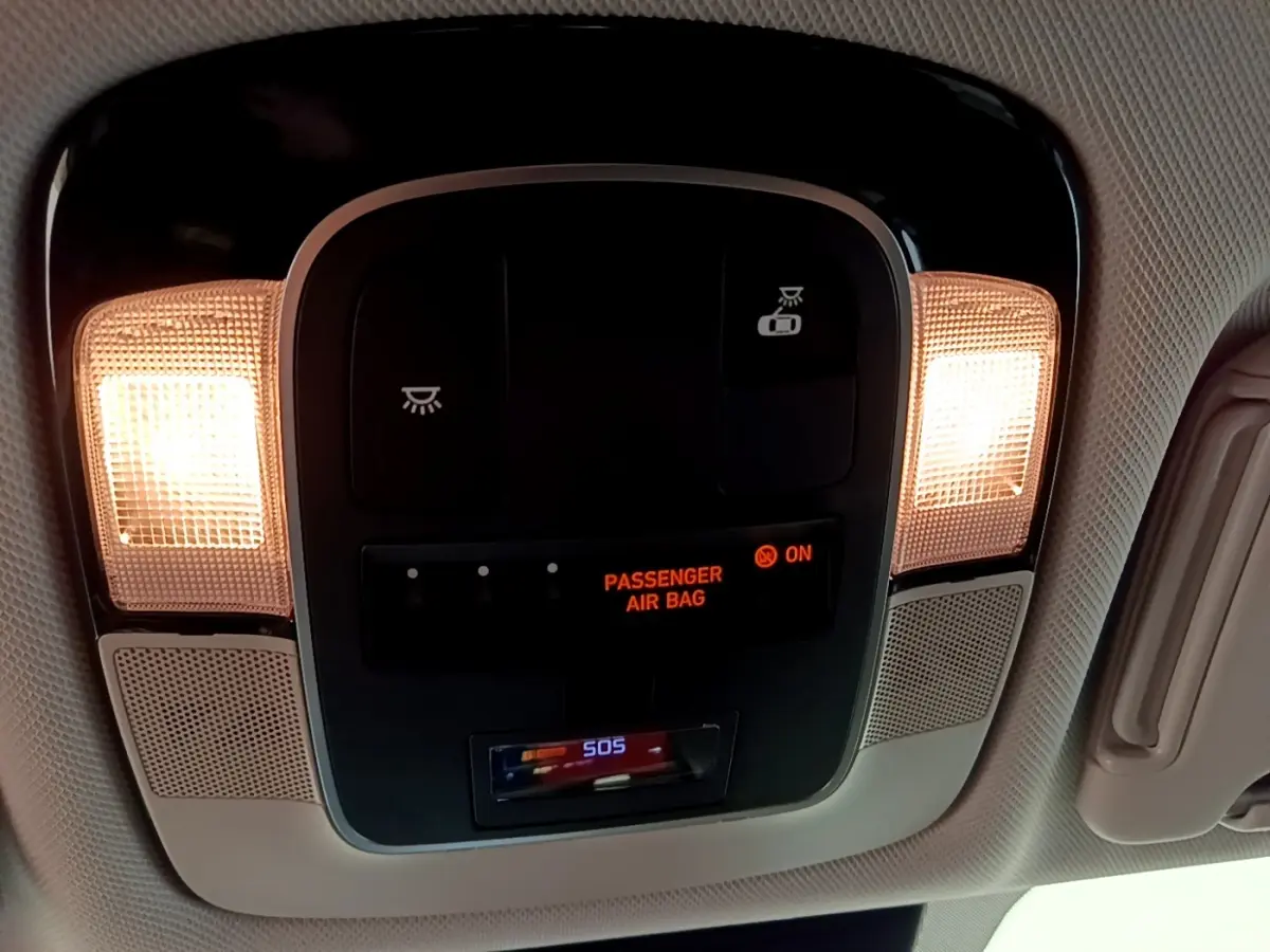 Vue intérieure en gros plan du plafonnier avec éclairage et indicateur airbag passager allumé dans un Hyundai Tucson gris foncé.