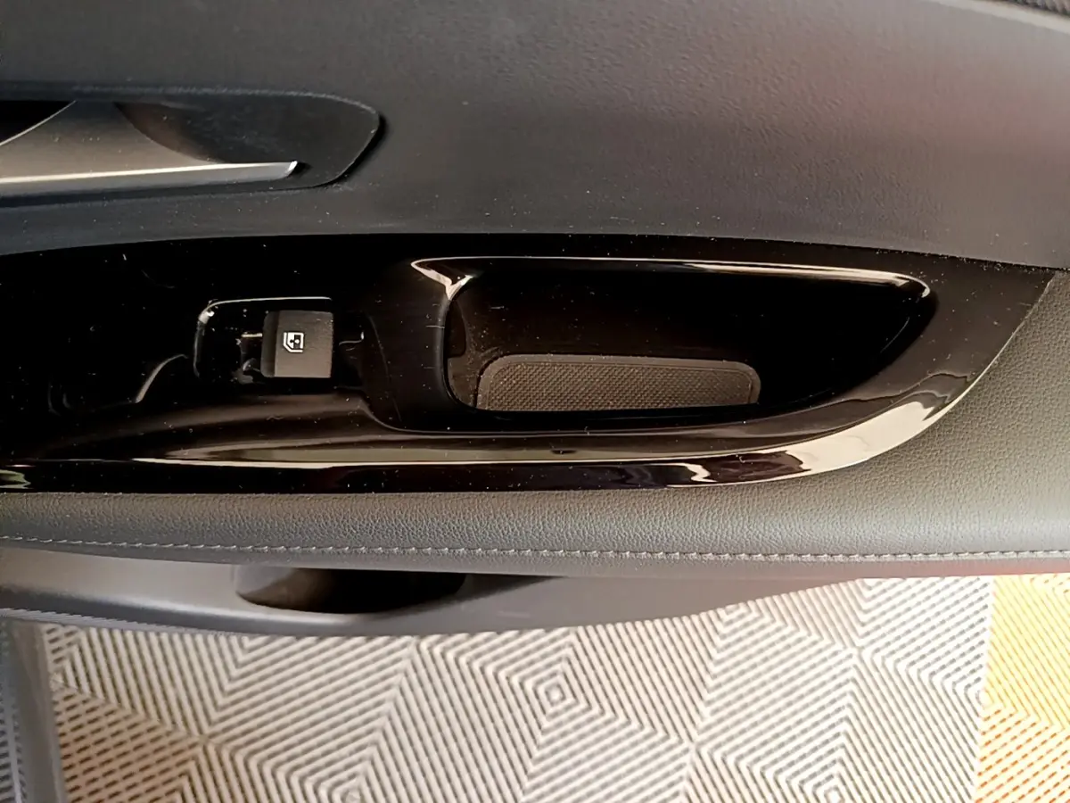 Poignée intérieure de porte côté gauche du Hyundai Tucson gris foncé, avec bouton de verrouillage des vitres.