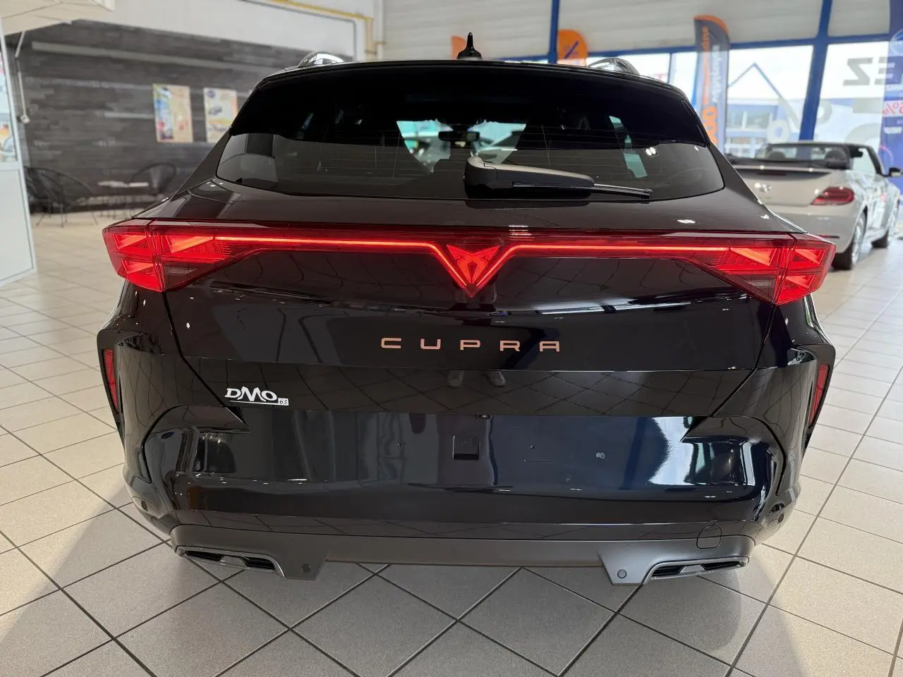 Vue arrière d'un CUPRA Formentor noir Night avec feux arrière en bandeau lumineux Tri-LED et double sortie d'échappement.