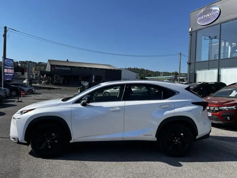 Profil latéral droit du Lexus NX 300H blanc nacré avec jantes noires, garé en extérieur sous un ciel bleu.