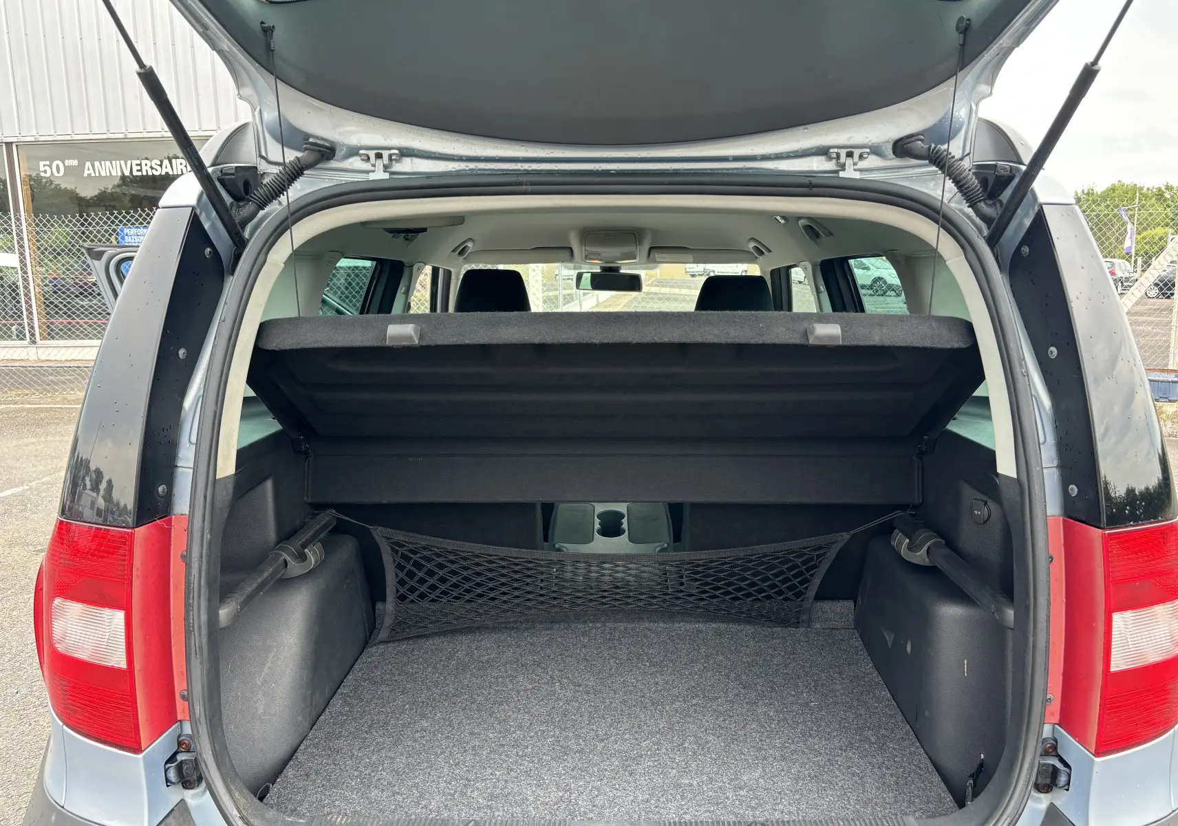 Coffre ouvert vu de l'arrière d'un Skoda Yeti gris 2012, avec filet de rangement et banquette arrière visible.