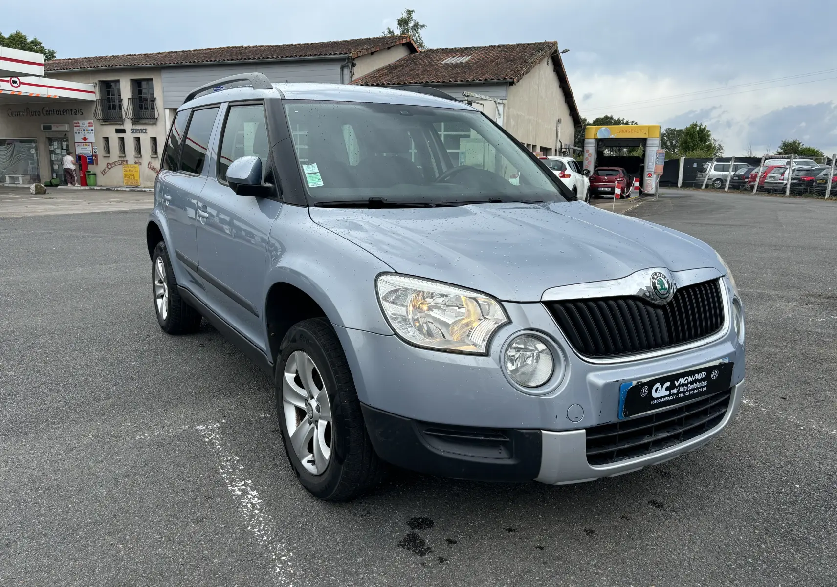 Vue 3/4 avant gauche d'un Skoda Yeti gris 2012 avec toit ouvrant et jantes alliage sur parking.