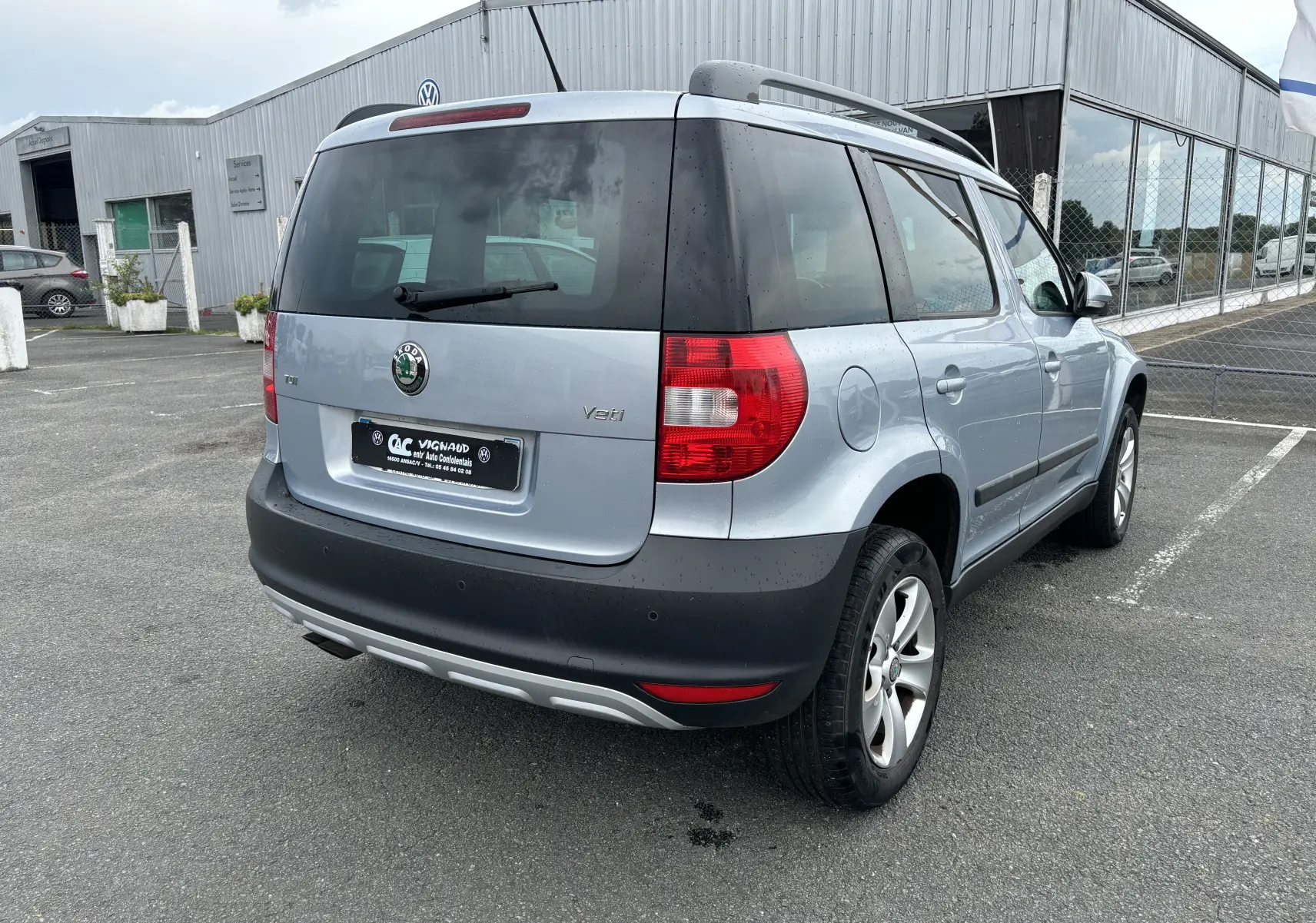 Vue 3/4 arrière droite d'un Skoda Yeti gris 2012 avec hayon noir et jantes alliage sur parking.