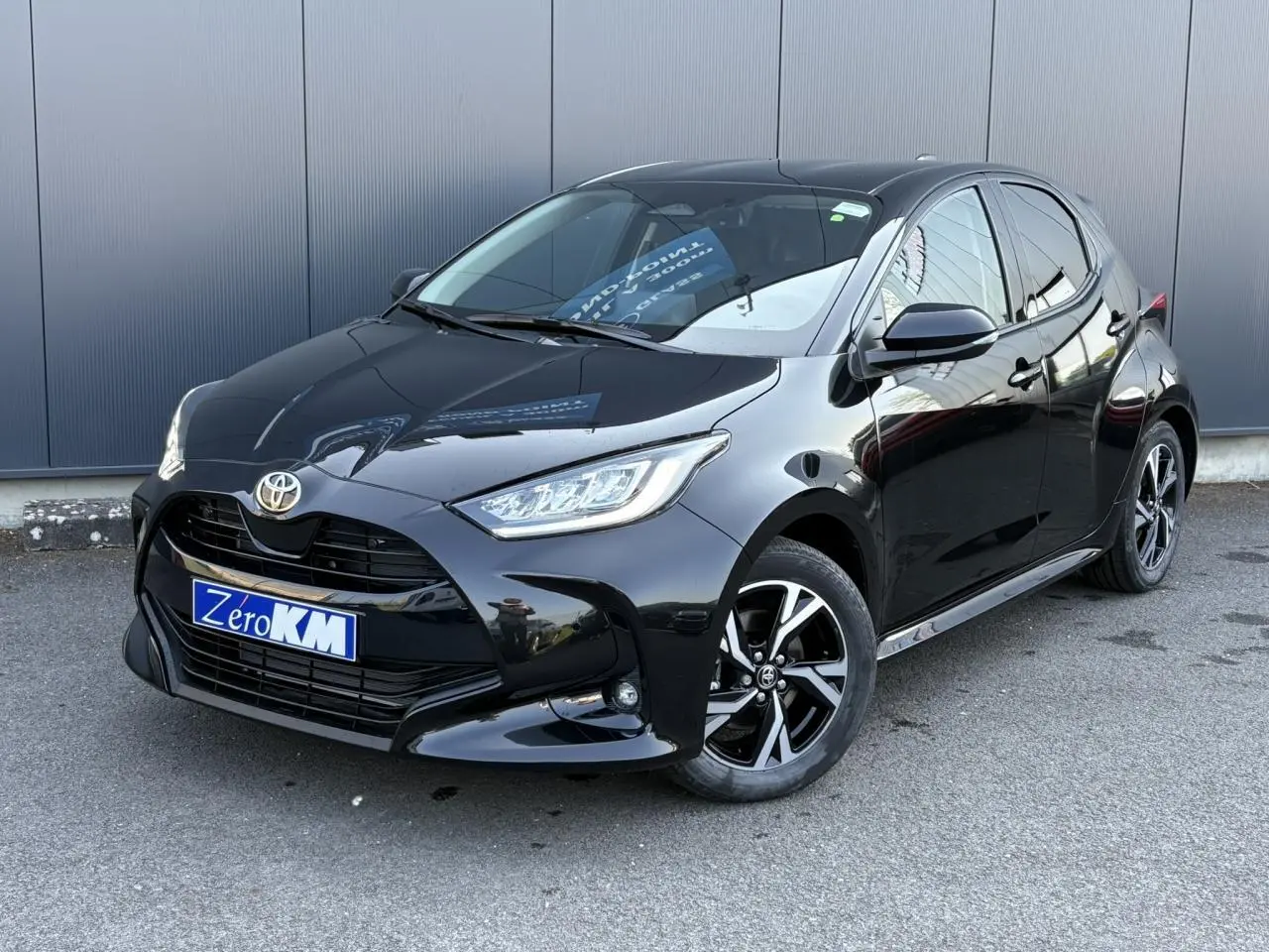 Toyota Yaris hybride noire vue en 3/4 avant droit avec jantes alliage et calandre noire brillante.