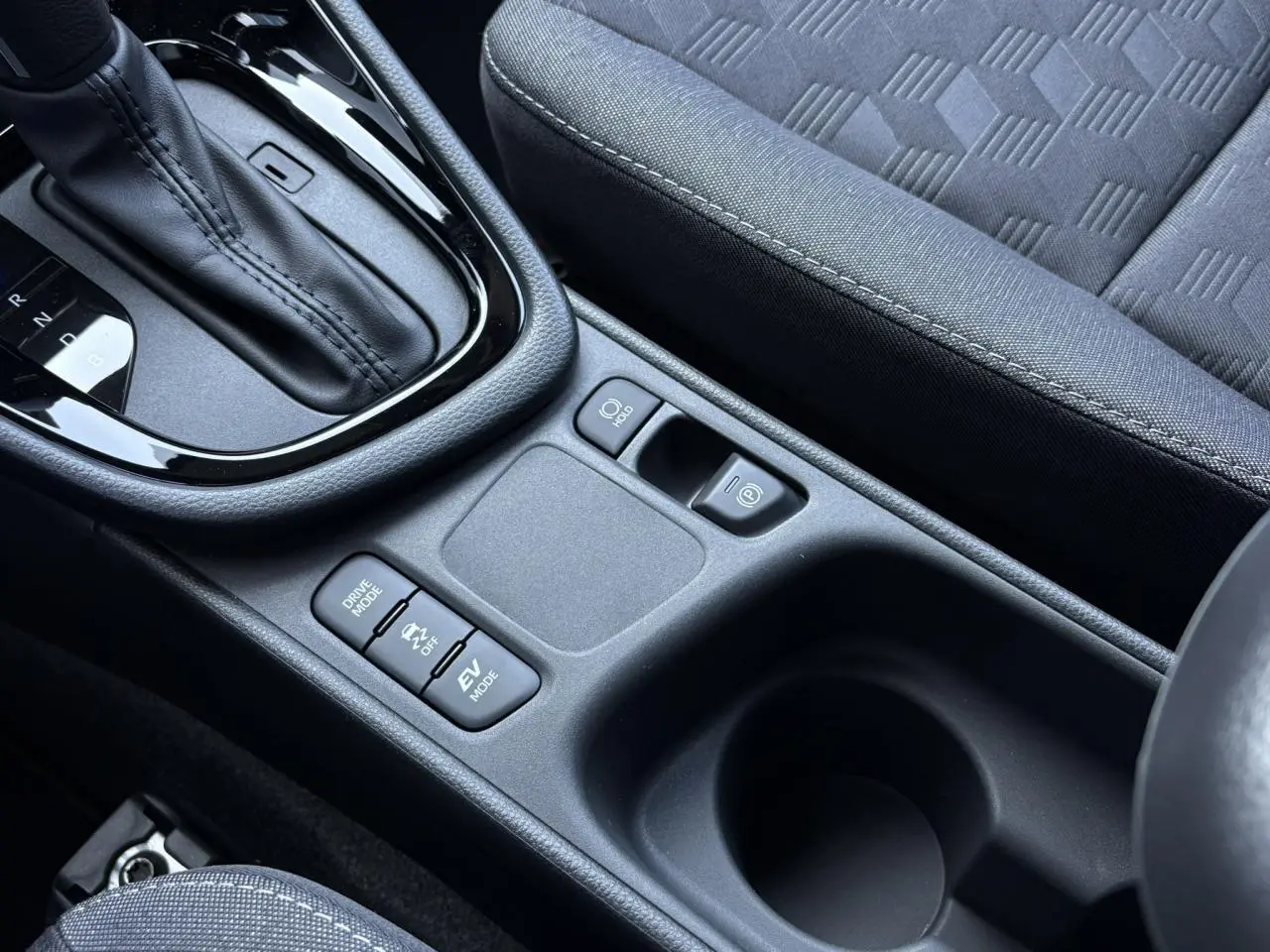 Gros plan sur la console centrale de la Toyota Yaris Hybride 2025, montrant levier de vitesses et commandes de modes de conduite.