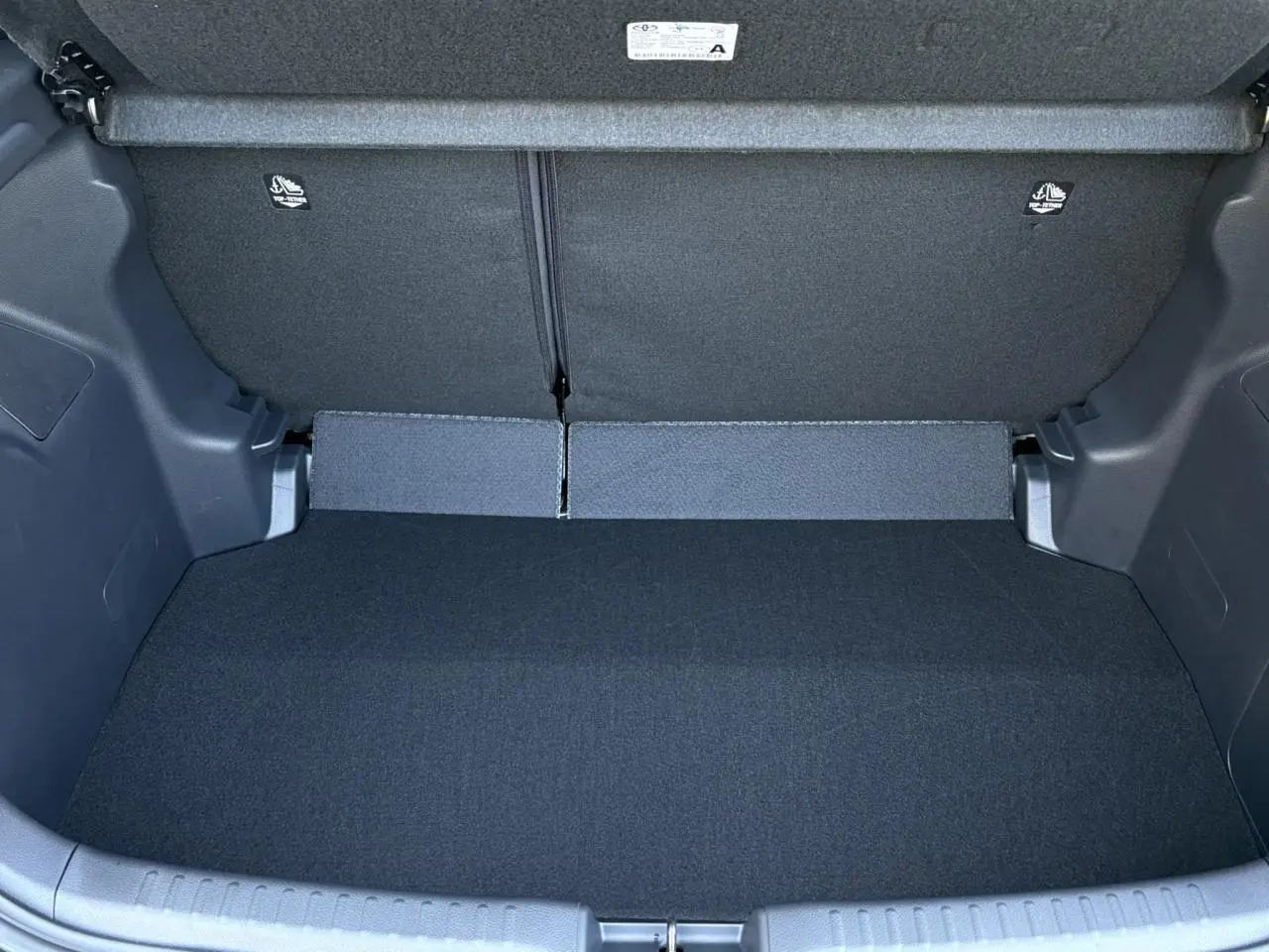 Coffre ouvert de la Toyota Yaris Hybride 2025, vue intérieure montrant un espace de chargement propre et noir.