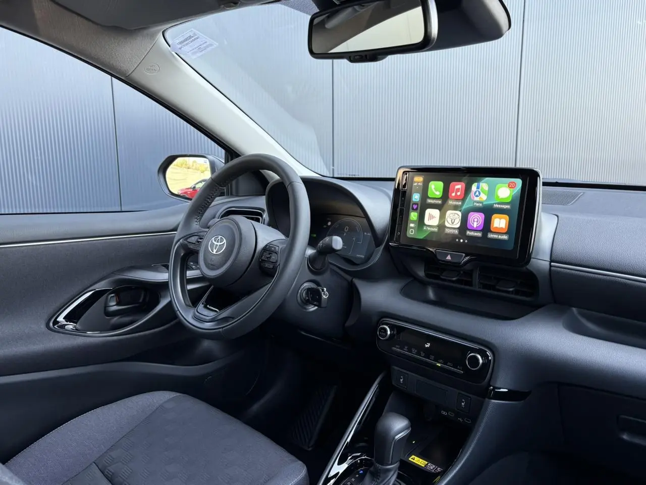 Intérieur de la Toyota Yaris Hybride 2025 vue côté conducteur, avec écran tactile et volant cuir noir.