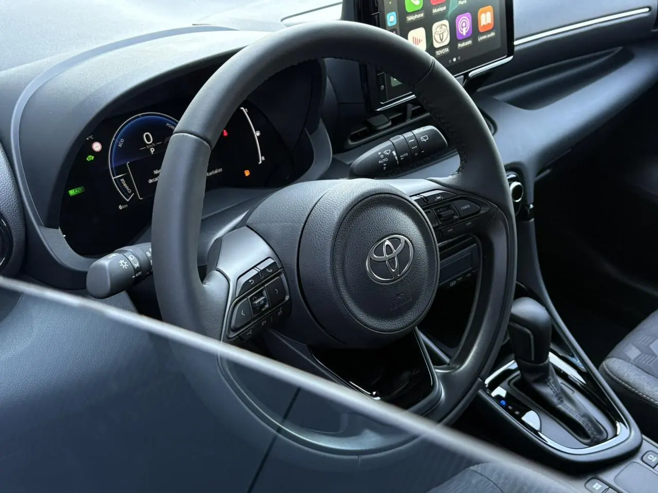 Vue rapprochée du volant cuir et du tableau de bord numérique de la Toyota Yaris Hybride 2025 noir intense.