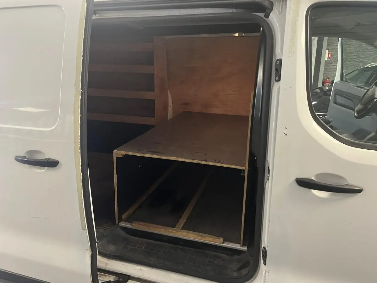 Vue intérieure côté droit du Peugeot Expert Fourgon blanc 2020 avec plancher bois antidérapant et cloison tôlée visible.