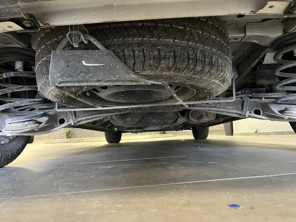 Vue en contre-plongée sous un Peugeot Expert Fourgon blanc, montrant la roue de secours et la suspension arrière.