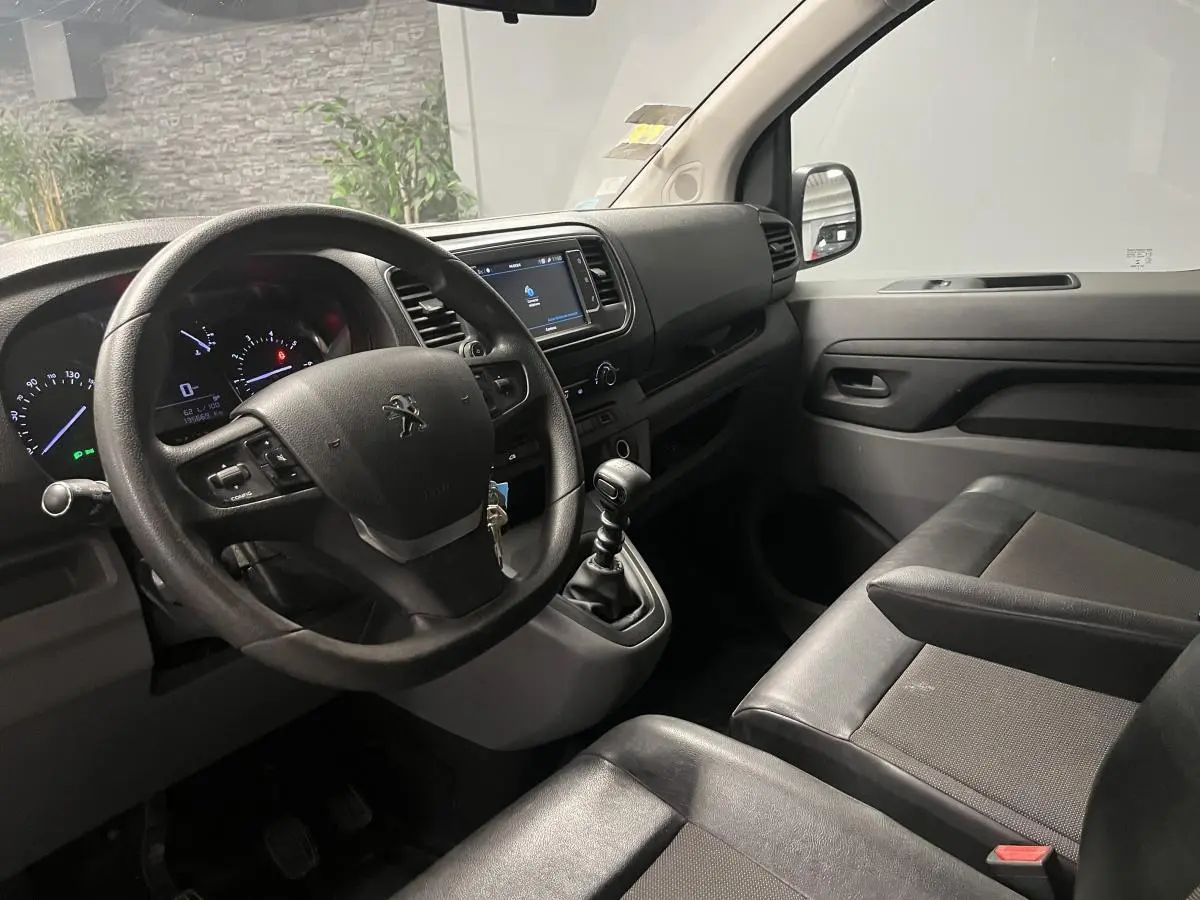 Vue intérieure côté conducteur du Peugeot Expert Fourgon 2020, volant multifonction et sièges tissu noir.