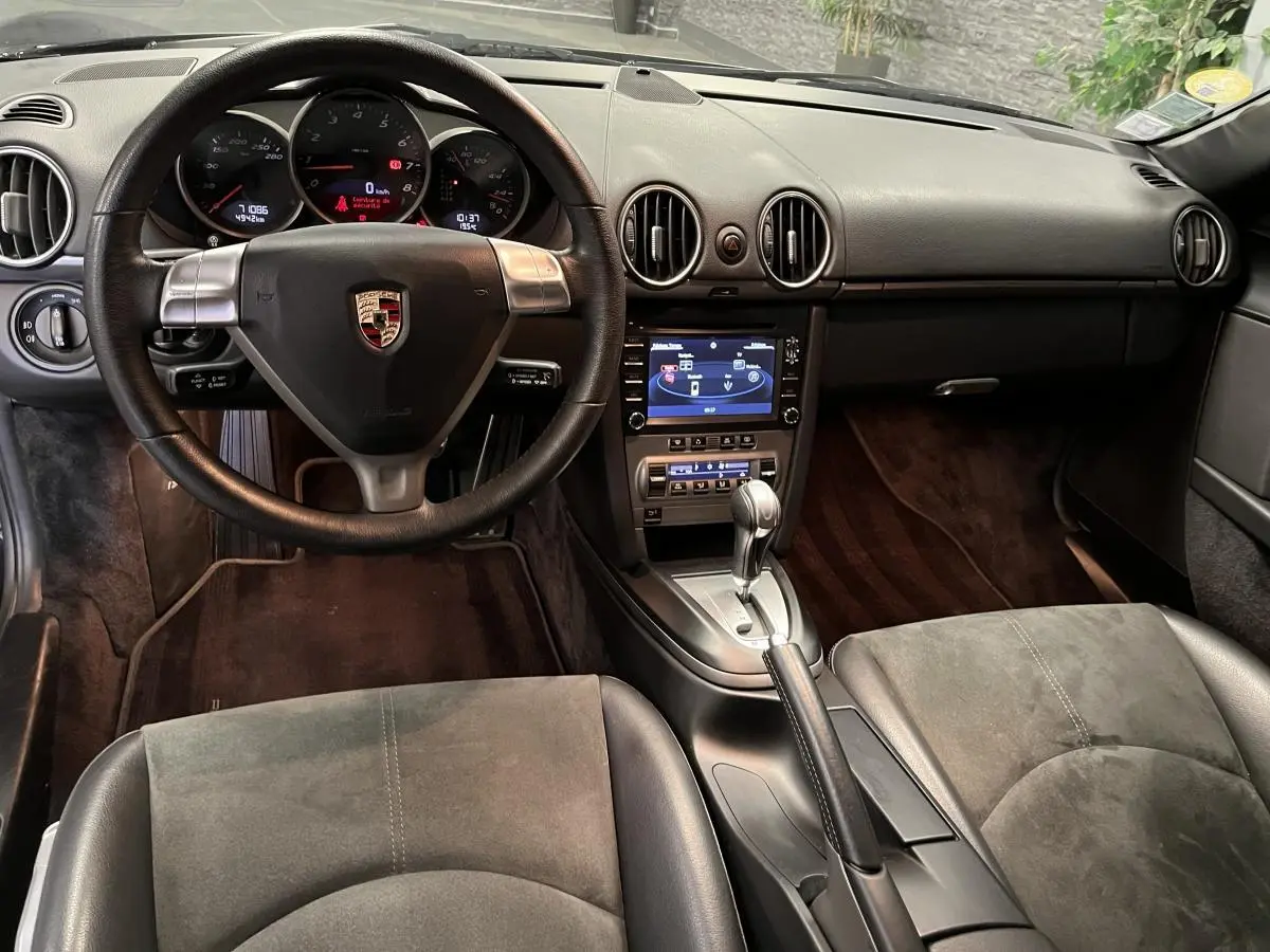 Intérieur noir de Porsche Cayman 987 2008, vue frontale sur volant, tableau de bord et console centrale avec levier automatique.