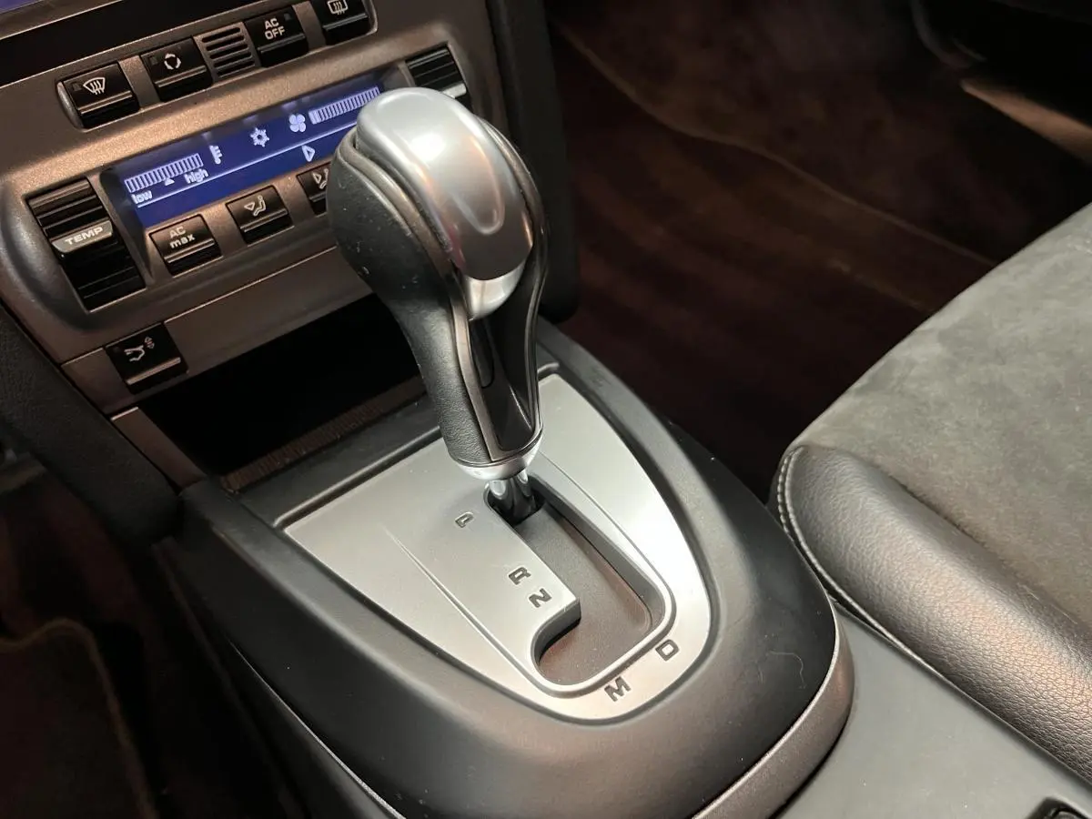 Le levier de vitesse automatique argenté et noir de la Porsche Cayman 2.7i 2008 vu de près dans l'habitacle.