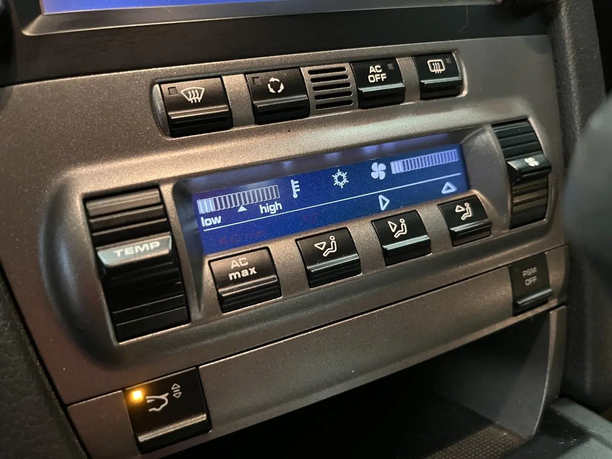 Détail de la console centrale du Porsche Cayman 987 noir, affichage digital de la climatisation et boutons de réglage.