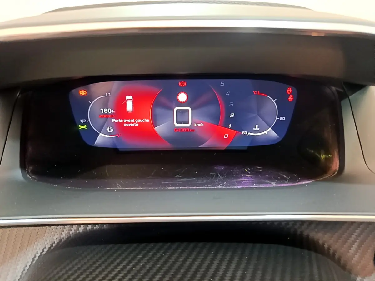 Tableau de bord numérique de Peugeot 208 blanc, affichage multifonctions avec alerte porte avant gauche ouverte.