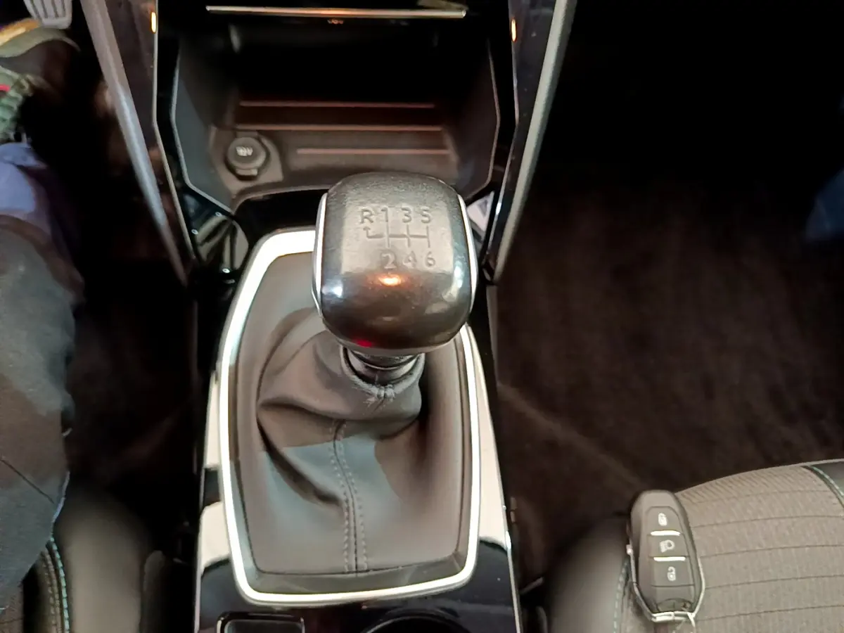 Le levier de vitesses manuel noir vu de dessus dans l'habitacle d'une Peugeot 208 blanche de 2020.