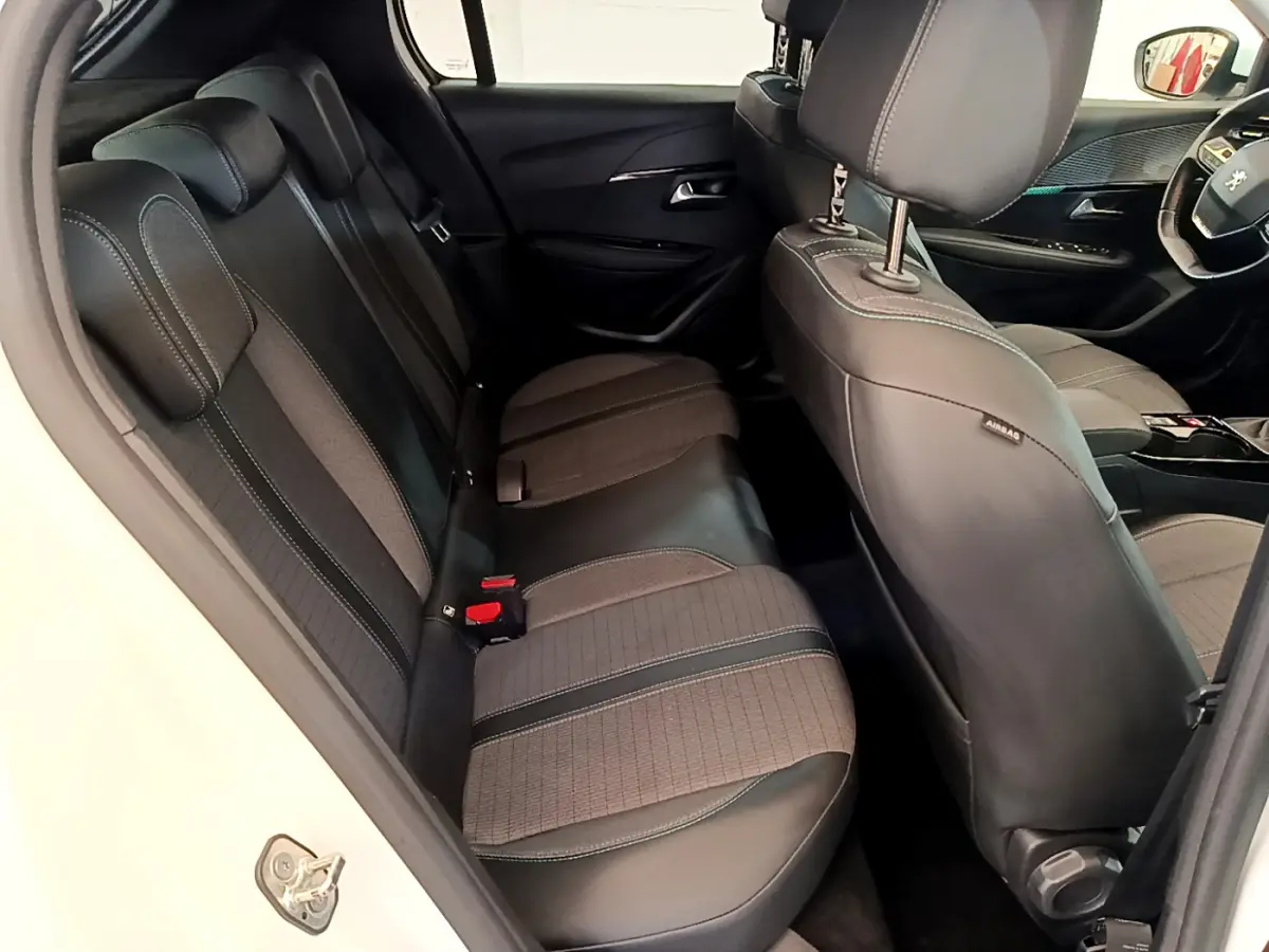 Vue intérieure côté gauche sur la banquette arrière et siège avant gris anthracite d'une Peugeot 208 blanche 2020