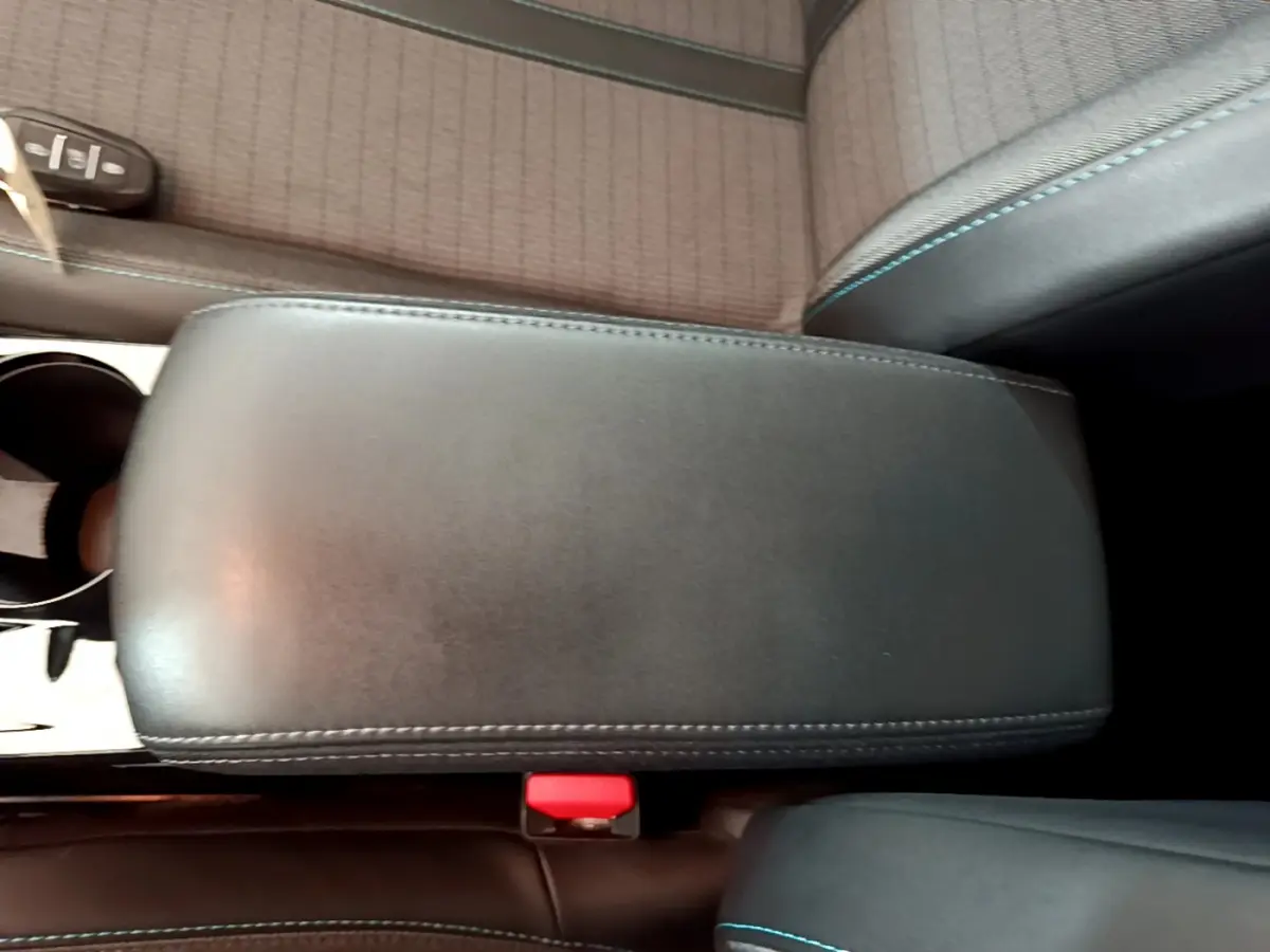 Accoudoir central noir avec surpiqûres bleues dans l'habitacle d'une Peugeot 208 blanche PureTech 100 S&S Allure Business 2020