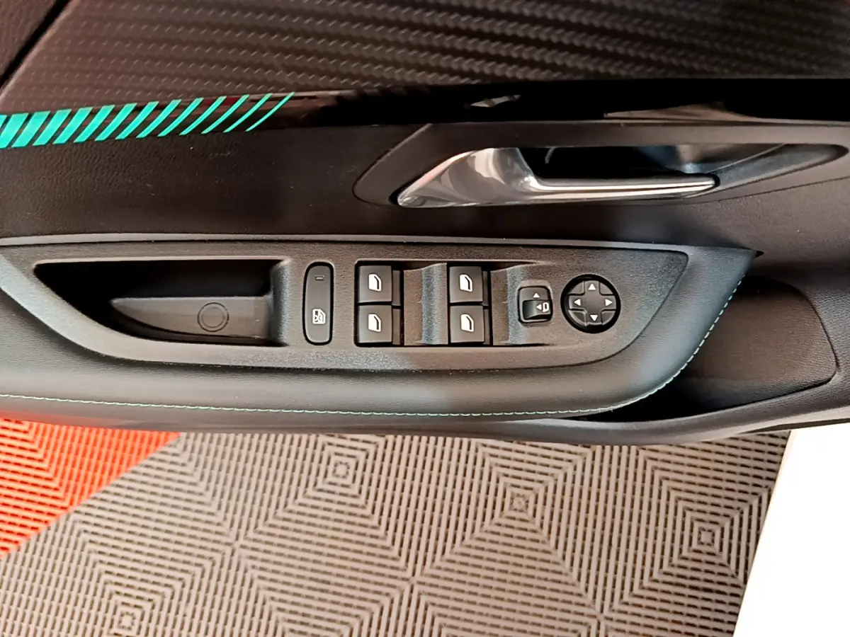 Gros plan sur la commande des vitres côté conducteur de la Peugeot 208 blanche, avec poignée de porte chromée.