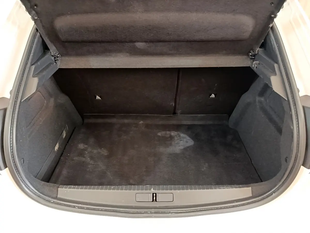 Coffre ouvert noir vu de face sur Peugeot 208 blanc, montrant l'espace de chargement vide et propre.