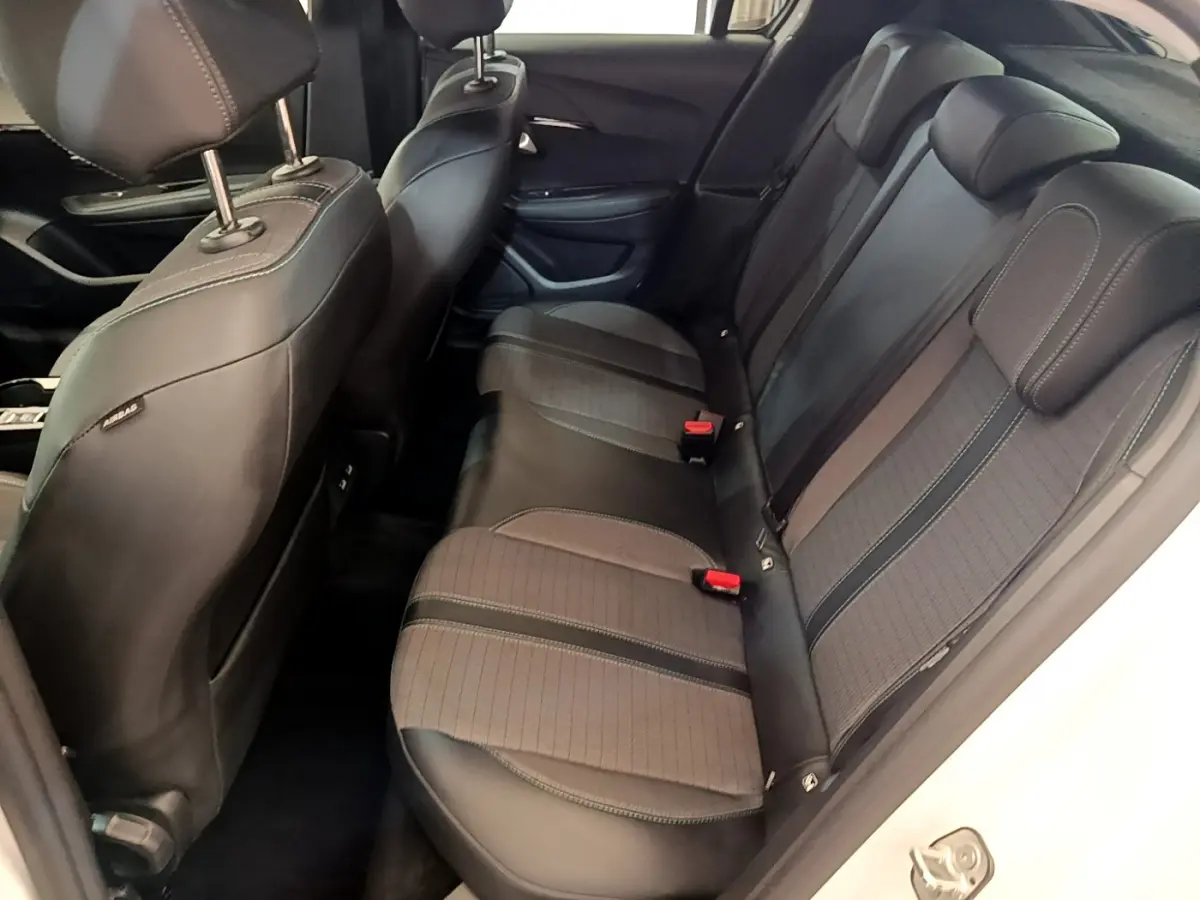 Vue côté droit de la banquette arrière noire et grise du Peugeot 208 blanc, avec appuie-têtes et ceintures visibles.