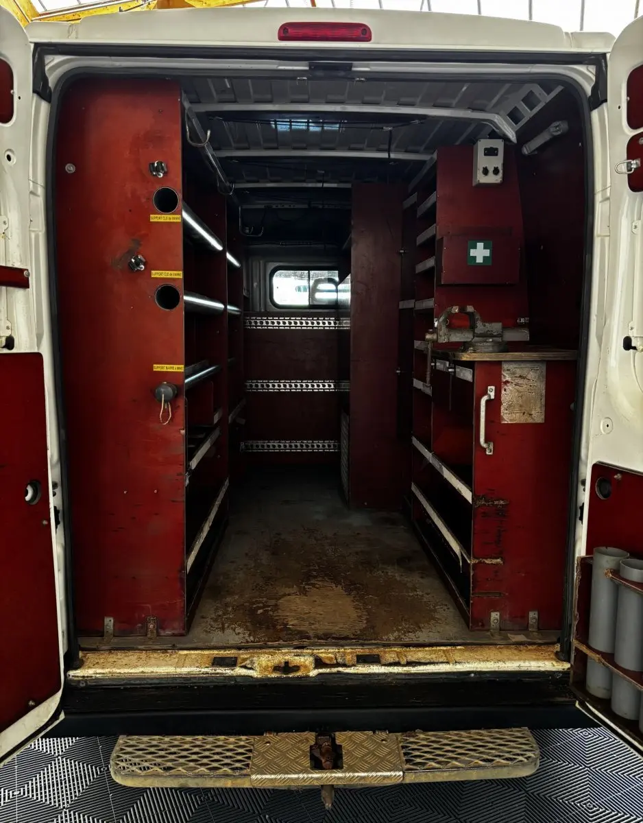 Vue arrière ouverte du Citroën Jumper blanc montrant l'intérieur aménagé avec étagères rouges et espace de rangement.
