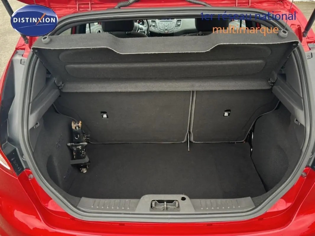 Coffre ouvert d'une Ford Fiesta rouge vue de l'arrière, montrant l'espace de chargement et l'intérieur noir.