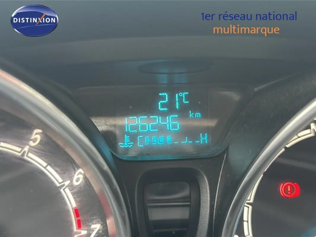 Gros plan sur le tableau de bord numérique bleu de la Ford Fiesta rouge, affichant 126246 km et 21°C.