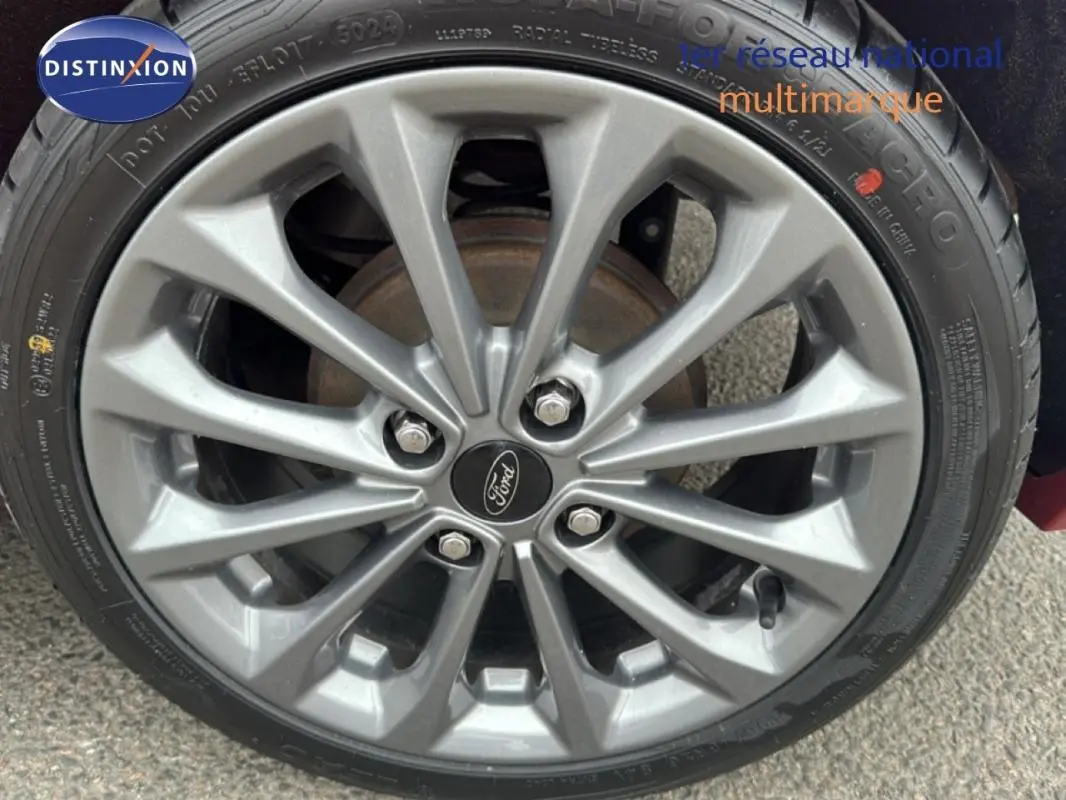 Gros plan sur la jante alliage 16 pouces grise de la Ford Fiesta rouge, avec logo Ford au centre.