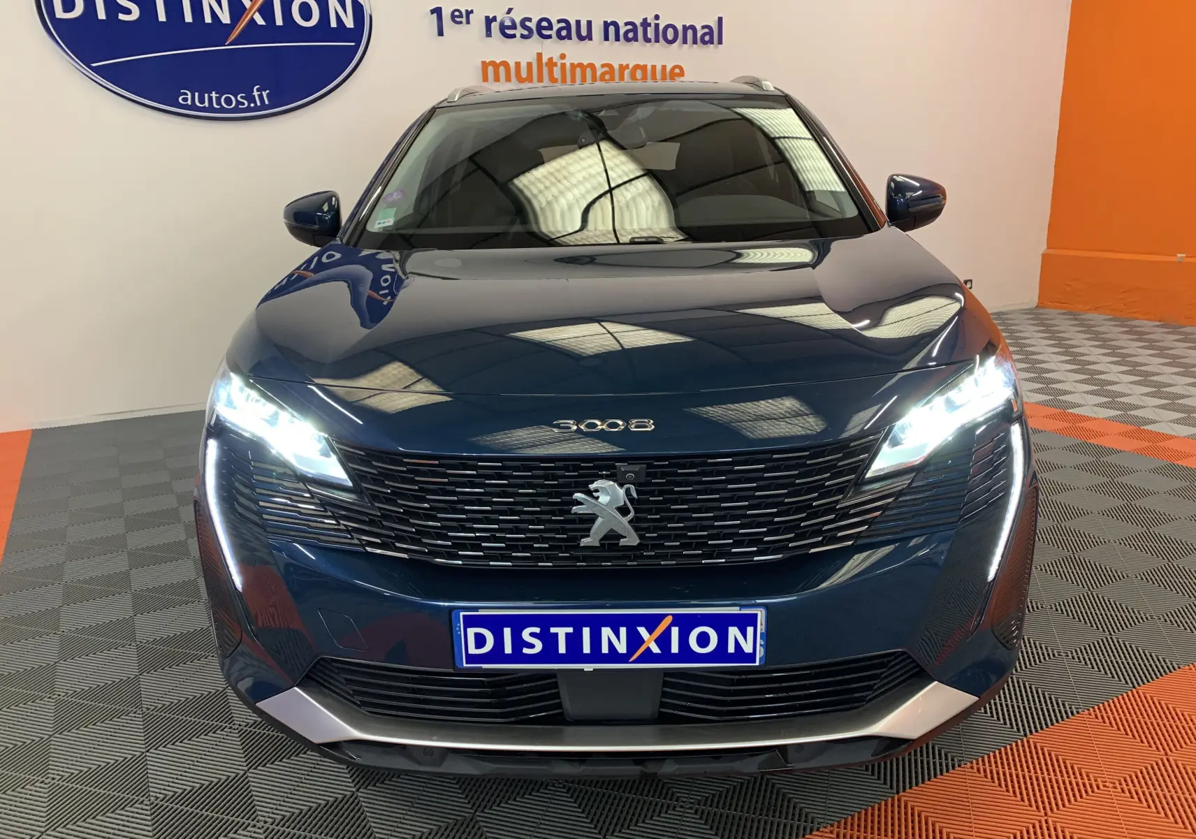 Vue frontale d'un Peugeot 3008 bleu Célèbes avec phares LED allumés dans un showroom.
