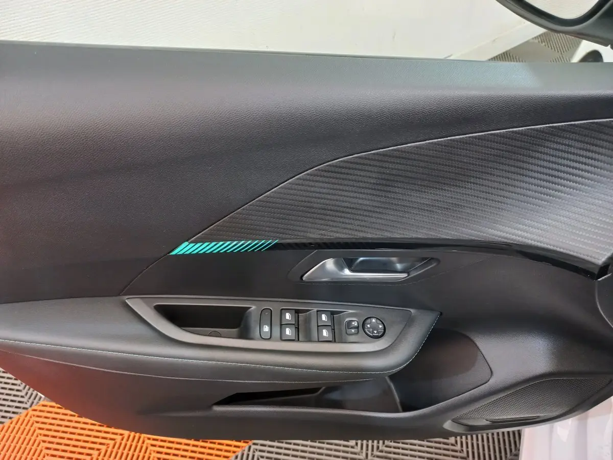 Vue rapprochée de la porte avant gauche noire avec insert carbone et commandes des vitres du Peugeot 208 blanc.